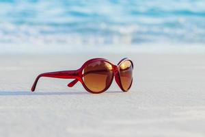Brown sunglasses on sand beautiful summer beach photo