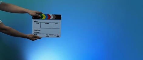 Hand holds empty film making clapperboard on color background in studio photo