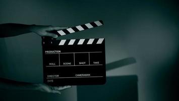 Hand holds empty film making clapperboard on color background in studio photo