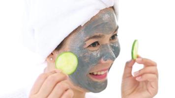 Video camera filming woman in white bathrobe applying a face mask for movie, behind the scenes of shoot