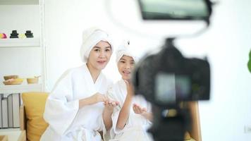 Video camera filming happy mom and daughter in white bathrobe acting for movie, behind the scenes of shoot