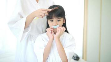 Happy beautiful mom in white bathrobe making her daughter hair at home, Family and Beauty Concept video