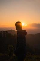 Traveler man standing on mountain peak in the sunset photo