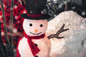 Snowman with hat and scarf in snowfall on Christmas festival photo