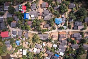 Top view of neighborhood traditional rural village of tribe local people on the hillside surrounded by forest in faraway photo