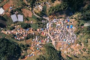 Top view of neighborhood traditional rural village of tribe local people on the hillside surrounded by forest in faraway photo