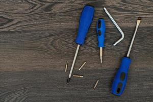 A set of tools on a dark wooden background. Construction, equipment, workplace. The composition of a flat layer. Screwdriver, tape measure, hexagon, attachments. photo