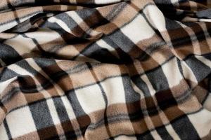 Wrinkled black and brown checkered clothing background. Fabric with a pattern of black white brown cells. photo