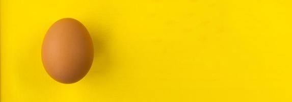 el huevo es marrón aislado en un fondo amarillo con espacio para tu texto foto