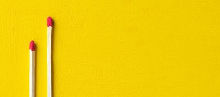 Two matches isolated on a yellow background close up with a blank space for your text photo