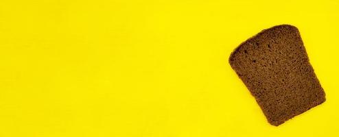 A slice of rye bread isolated on a yellow background close up with a blank space for your text photo