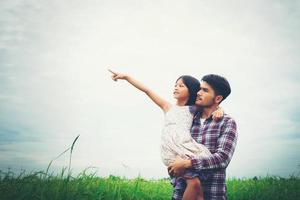Daughter pointing away and smiling with her dad in the meadows field. photo