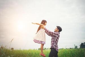 papá cargando a su hija con la naturaleza y la luz del sol, disfruta de la familia. foto