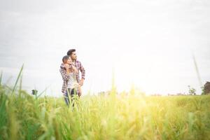 Young hipster couple standing on field pointing look away to the sky, couple in love. photo