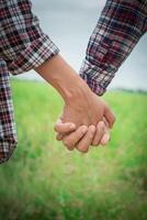 Close Up of loving hipster couple holding hands while walking at meadows field. photo