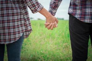 Close Up of loving hipster couple holding hands while walking at meadows field. photo