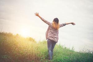 Young beautiful hipster woman in a flower field at sunset. Freedom enjoying with nature. photo