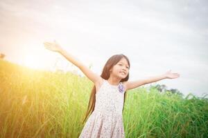 linda niña asiática de pie entre el día de sol del campo de flores púrpura. libertad disfrutando con la naturaleza. foto