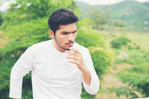 Young hipster man taking rest, smoking cigarette with nature and fresh breeze. photo