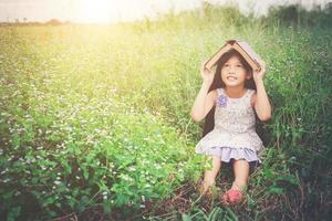 little cute asian girl cover book on her head at nature. photo