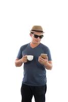 Young hipster man looking at his smart phone and coffee in hand isolated on white background. photo