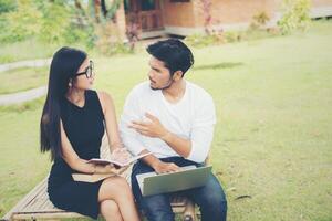 Young education couple sitting on the bench talk about study in the outdoors and good weather. photo