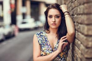 Young woman with blue eyes standing next to brick wall photo