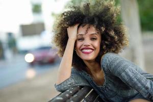 joven negra con peinado afro sonriendo en medio urbano foto