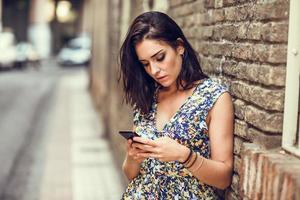 Serious young woman using her smart phone outdoors. photo