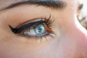 primer plano de los ojos azules de la mujer joven con pestañas largas foto