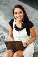 Student woman using laptop computer sitting on urban steps. photo