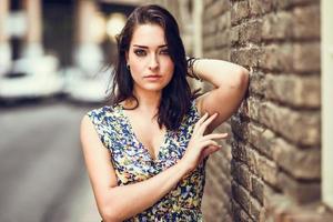 Girl with blue eyes standing next to brick wall outdoors photo