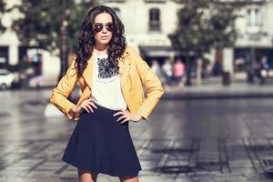 Young brunette woman with sunglasses in urban background photo