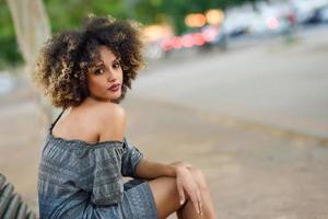 joven negra con peinado afro sonriendo en medio urbano foto