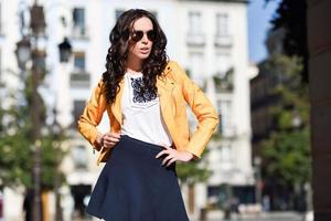 Young brunette woman with sunglasses in urban background photo