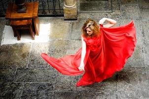 Beautiful blonde woman, wearing a red dress, jumping