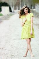 Beautiful blonde girl, dressed with a beige dress, standing in rural road photo