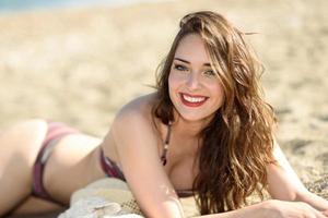 joven mujer sonriente tirada en la arena de la playa foto