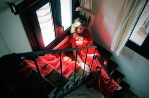 Beautiful blonde woman sitting in stairs wearing a red dress photo