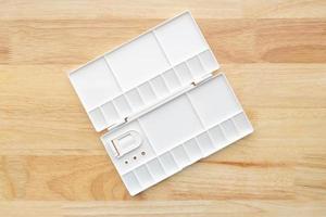 White watercolor palette. Empty watercolor tray isolated on wood background. photo