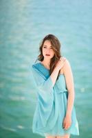 Woman with blue eyes wearing blue dress in the beach. photo