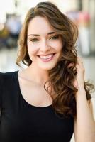 Beautiful young woman with blue eyes smiling in urban background photo