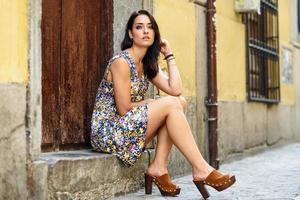Beautiful young woman with blue eyes sitting on urban step. photo