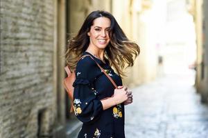 Young woman moving her long hair in urban background. photo