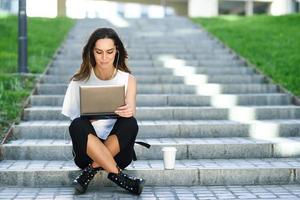 Young woman working with her laptop computer sitting on the floor. photo