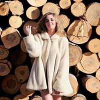 Beautiful blonde woman wearing a white coat on poplar trunks photo