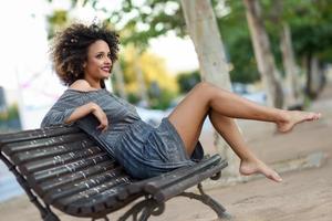 Young black woman with afro hairstyle smiling in urban background photo