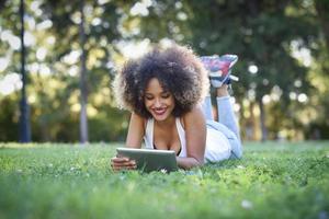 mujer mixta con peinado afro mirando su computadora de tableta foto