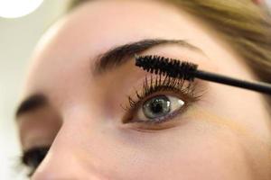 Make-up. Applying Mascara. Long Eyelashes and blue eyes photo