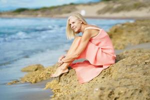 Slim senior woman on rocky seashore in summer photo